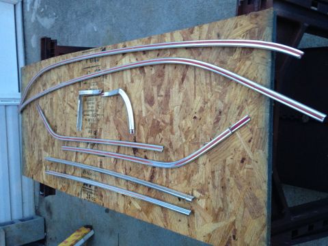 1971 Ford Ranchero - Several pieces of chrome trim with red pinstripes are laid out on a piece of plywood. The trim pieces appear to be for a vehicle, possibly…