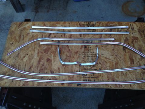 1971 Ford Ranchero - Several pieces of chrome and red pinstripe trim are laid out on a piece of plywood. The trim pieces appear to be for a vehicle, possibly fo…