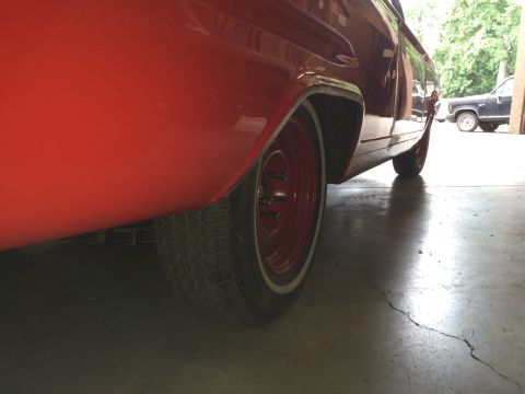 1964 Ford Fairlane - Close-up view of the rear wheel and lower body of a red vehicle.