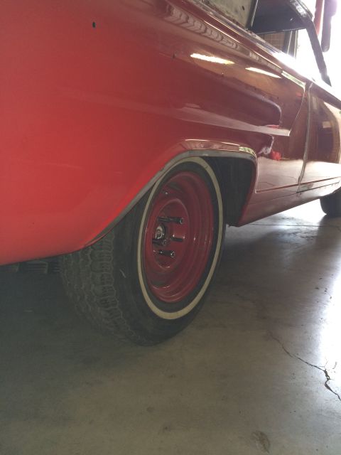 1964 Ford Fairlane - Close-up view of a red vehicle's fender and wheel, suggesting it is in a workshop or garage.