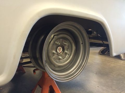 1964 Ford Fairlane - A vehicle's rear wheel is elevated on jack stands, revealing the underside and suspension components.
