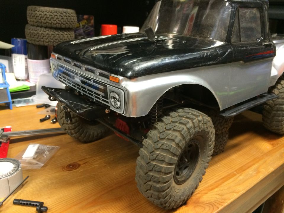 RC truck body with black and silver paint, off-road tires, and custom grille.