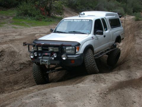 1996 Ford Bronco - This white Toyota Tacoma is equipped for off-road adventures, navigating a challenging dirt path.