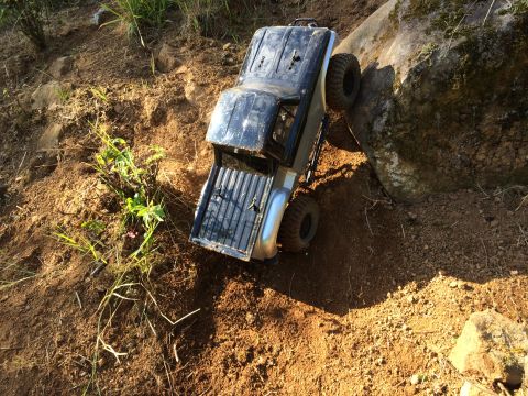1989 Ford Bronco - RC truck climbing over rocks and dirt on an outdoor trail.