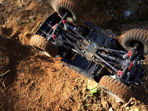 1989 Ford Bronco - RC rock crawler chassis with large tires stuck in muddy terrain.