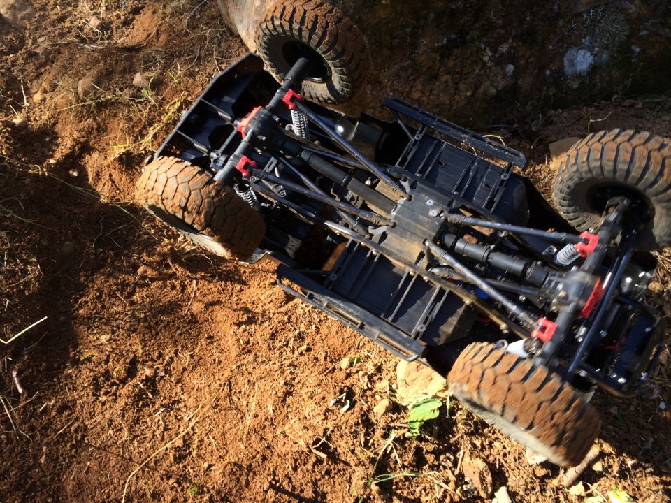 Underneath view of a remote control rock crawler chassis stuck in dirt
