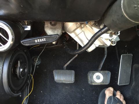 1965 Ford Mustang - The interior of a car shows the brake pedal, gas pedal, and a speaker. The brake pedal has the word BRAKE visible.