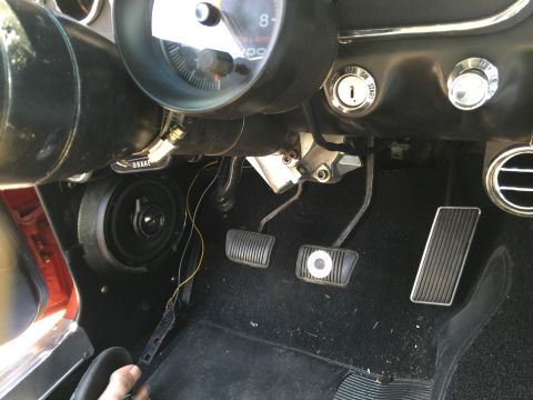 1965 Ford Mustang - Interior view of a 1965 Ford Mustang, showing the pedals, speaker, and dashboard gauges.