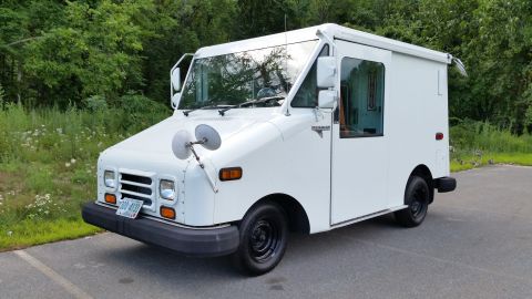 1991 Ford Crown Victoria LTD - A white walk-in van is parked on an asphalt surface with a wooded area behind it.