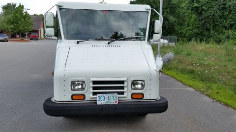 1991 Ford Crown Victoria LTD - A white delivery truck is parked on a paved surface with a grassy area to the right.