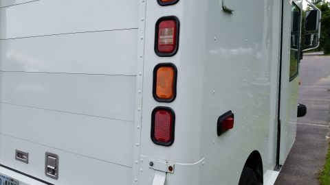 1991 Ford Crown Victoria LTD - The rear corner of a white box truck is visible, stacked red and amber lights and a large ribbed panel.