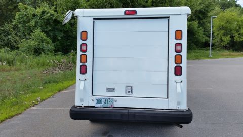 1991 Ford Crown Victoria LTD - White step van with a roll-up door and vertical taillights is parked on asphalt.