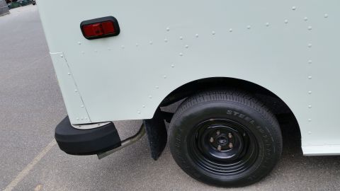 1991 Ford LTD Crown Victoria - Close-up of the rear wheel and taillight assembly on a white van.