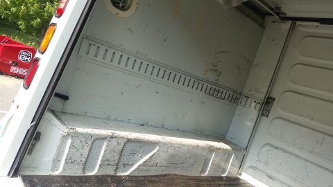 1991 Ford LTD Crown Victoria - The interior of a white cargo van is viewed from the rear, revealing the cargo space and tie-down rails.
