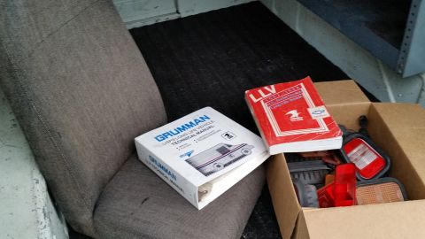 1991 Ford LTD Crown Victoria - Photograph of a Grumman technical manual and parts box resting on a vehicle seat, not a document scan itself.