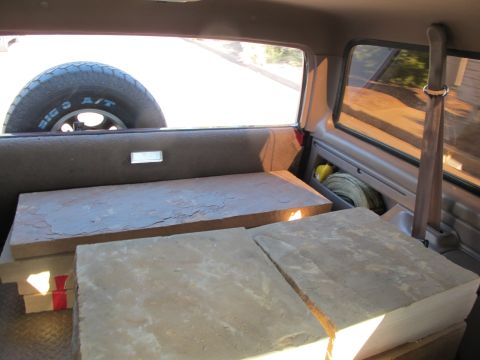 1996 Ford Bronco - The cargo area of an SUV is filled with stone slabs and a spare tire is mounted in the rear.