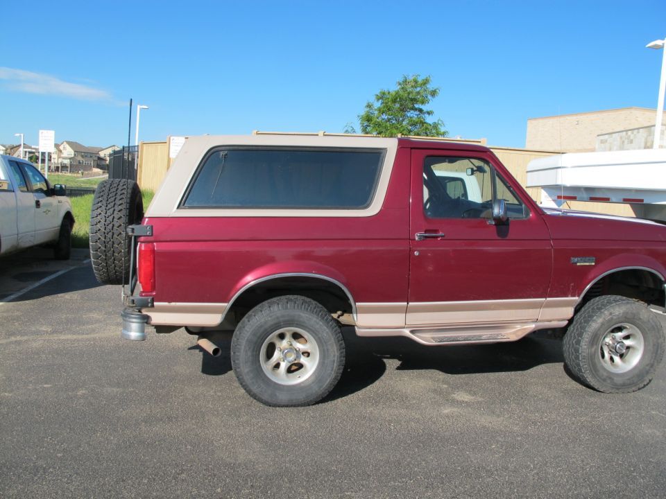 Red 1996 Ford Bronco side view with tan top and rear spare tire