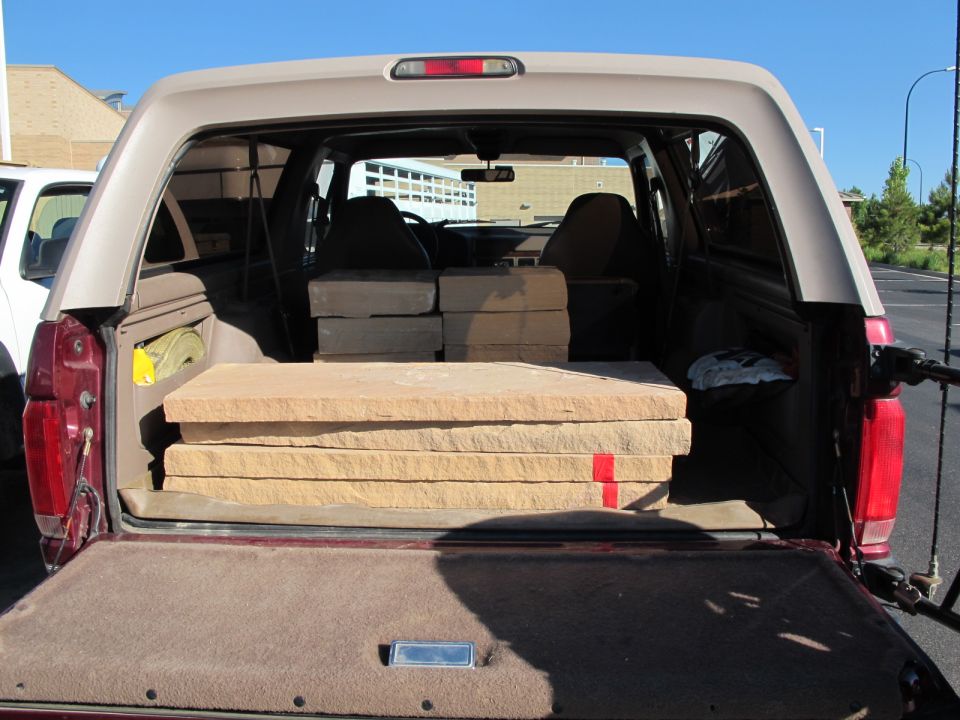 1996 Ford Bronco rear cargo area loaded with stone slabs, another vehicle visible to the left
