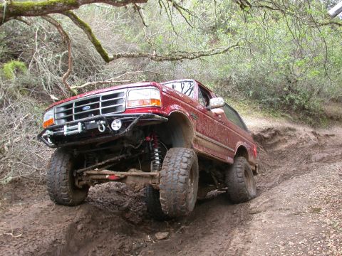 1996 Ford Bronco - This 1996 Ford Bronco is tackling a challenging muddy trail with its lifted suspension and off-road tires.