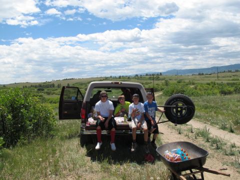 1996 Ford Bronco - A group of kids enjoy a sunny day outdoors, sitting in the back of a Ford Bronco with a spare tire mounted on the side.