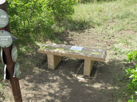 1996 Ford Bronco - A stone bench sits in a grassy area, marked with caution tape and a sign.