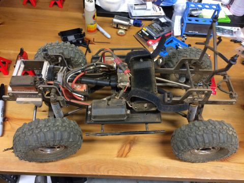 1989 Ford Bronco - RC crawler chassis with large tires and suspension components laid out on a workbench.