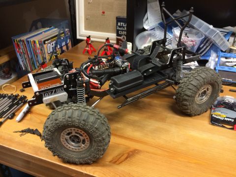 1989 Ford Bronco - RC rock crawler chassis with visible electronics and suspension parts on a workbench.