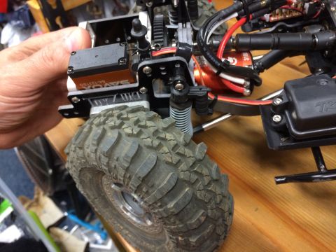 1989 Ford Bronco - A servo motor and a large, knobby tire are visible on this remote control car part.