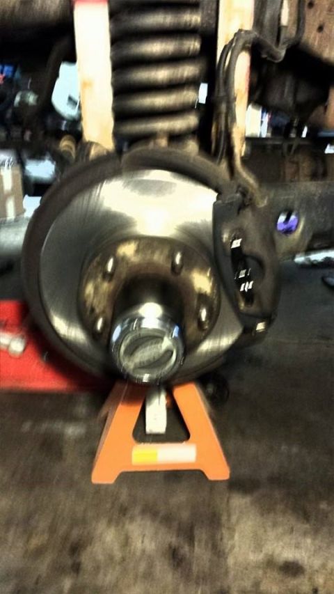1996 Ford Bronco - Vehicle brake rotor and hub assembly on a jack stand, showing suspension components.