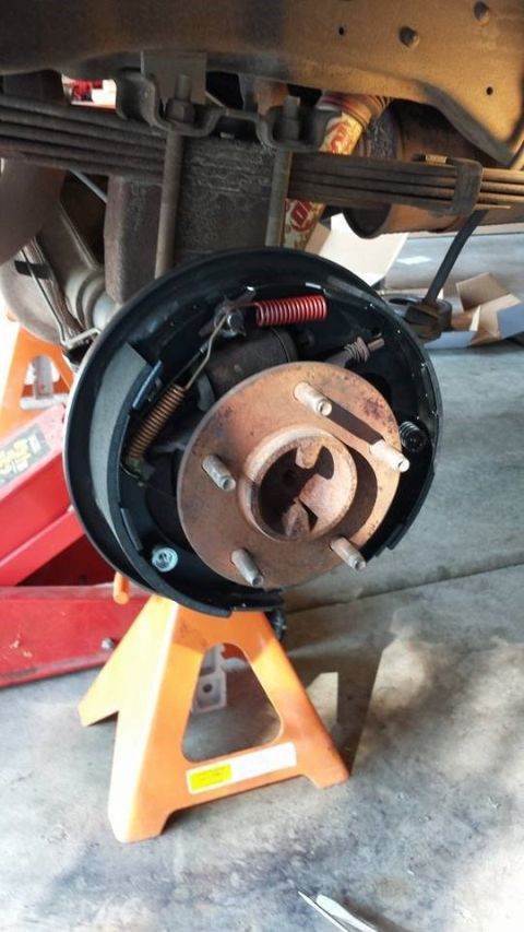 1996 Ford Bronco - Vehicle's rear drum brake assembly is disassembled and supported by jack stands for maintenance.