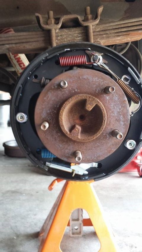 1996 Ford Bronco - The rear brake drum assembly of a vehicle is shown, supported by an orange jack stand.