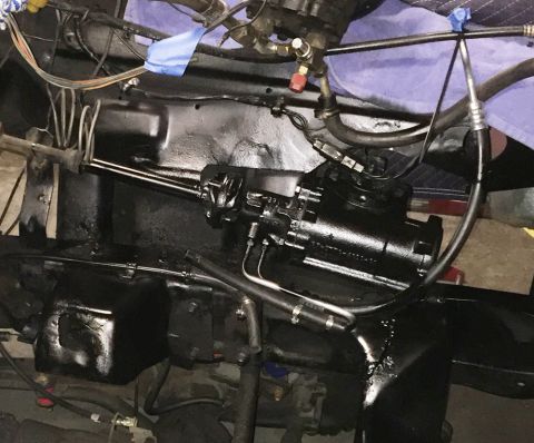 1978 Ford Bronco - A black painted steering gear box assembly is mounted to the frame of a vehicle, with hydraulic lines and wiring connected.