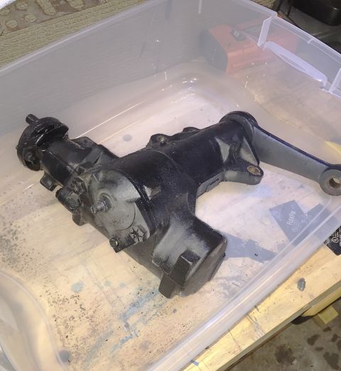 1978 Ford Bronco - A black steering gear box with a gray arm is shown inside a clear plastic bin.