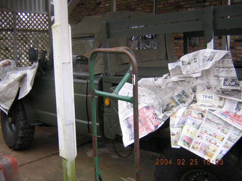 1984 Chevrolet Blazer - A military-style truck is partially covered with newspaper, suggesting it is being prepped for painting or protection.