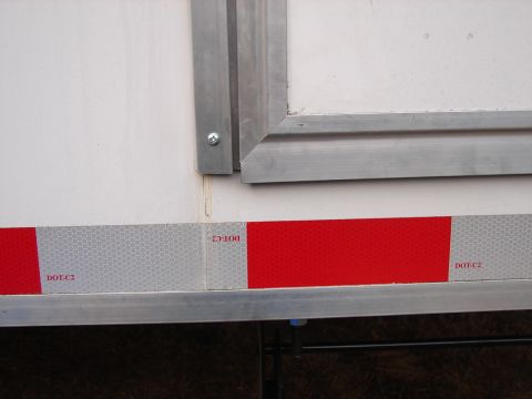 1973 Ford Ranchero - Close-up of a trailer's side panel showing DOT-C2 reflective tape and metal trim.