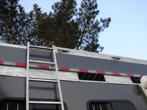 1973 Ford Ranchero - A gray trailer is shown with a ladder attached to its side and reflective tape along its upper edge.