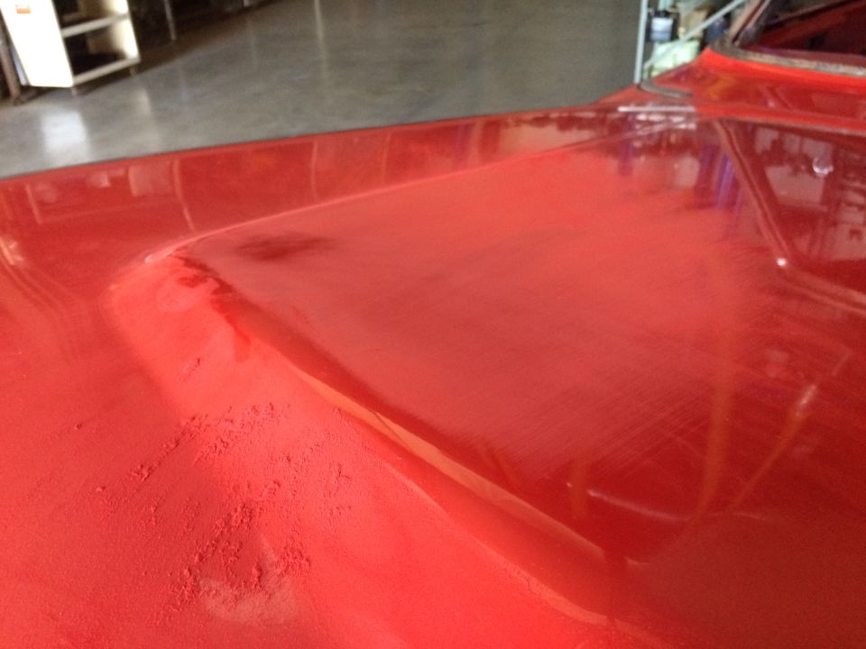 Close-up of a red car hood with some dust and imperfections