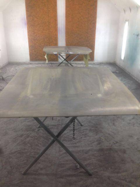 1964 Ford Fairlane - Car hoods are prepped for painting inside a booth, with one hood in the foreground and another in the background.