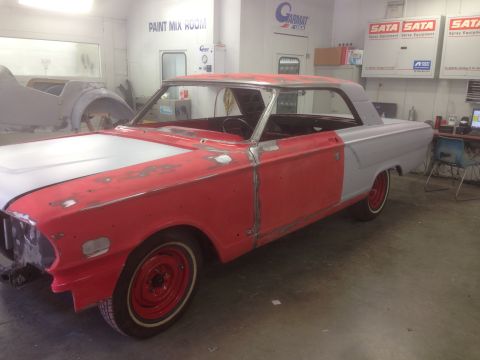 1964 Ford Fairlane - A 1964 Ford Fairlane coupe body is prepped for paint in a workshop, showing its two-tone red and gray primer finish.