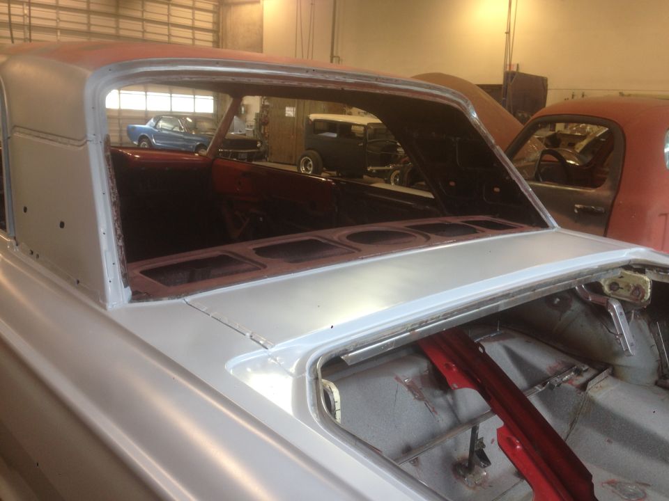 1964 Ford Fairlane interior and roofline, undergoing restoration. Another blue car is visible in the background