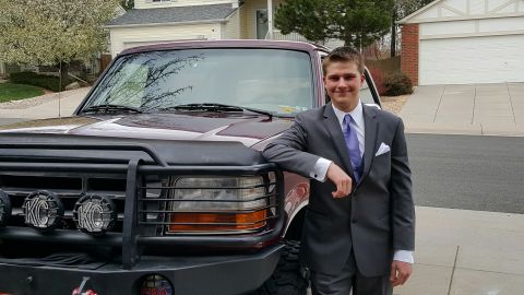 1996 Ford Bronco - A young man in a suit poses next to a maroon Ford Bronco with a custom bull bar and auxiliary lights.