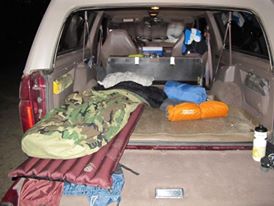 1996 Ford Bronco - The rear cargo area of an SUV is filled with camping equipment, suggesting preparation for an outdoor adventure.