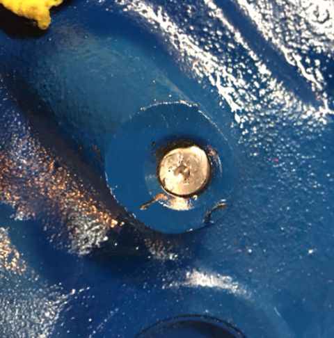 1978 Ford Bronco - A close-up shot shows a silver Phillips head screw set into a circular recess on a textured, glossy blue painted surface. The screw appears…
