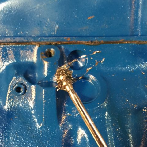 1978 Ford Bronco - A close-up shot shows a drill bit with metal shavings being removed from a blue engine block. The drill bit is actively cutting into a thre…