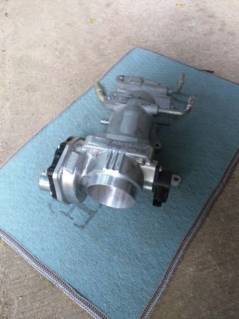 2007 Ford Crown Victoria - A silver performance throttle body labeled "POWER-PLUS 70mm" is shown resting on a blue microfiber cloth placed on a concrete surface.