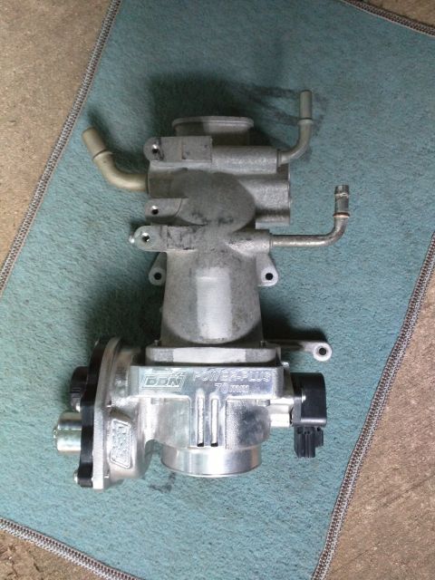 2007 Ford Crown Victoria - A polished aluminum BBK Power-Plus 70mm throttle body is shown mounted on a teal mat. The throttle body features a black electrical connect…