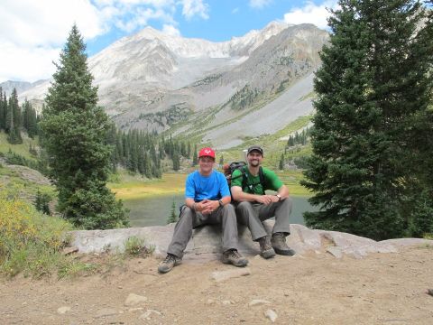1996 Ford Bronco - Two men are sitting on a rock in front of a mountain lake and a large mountain range.
