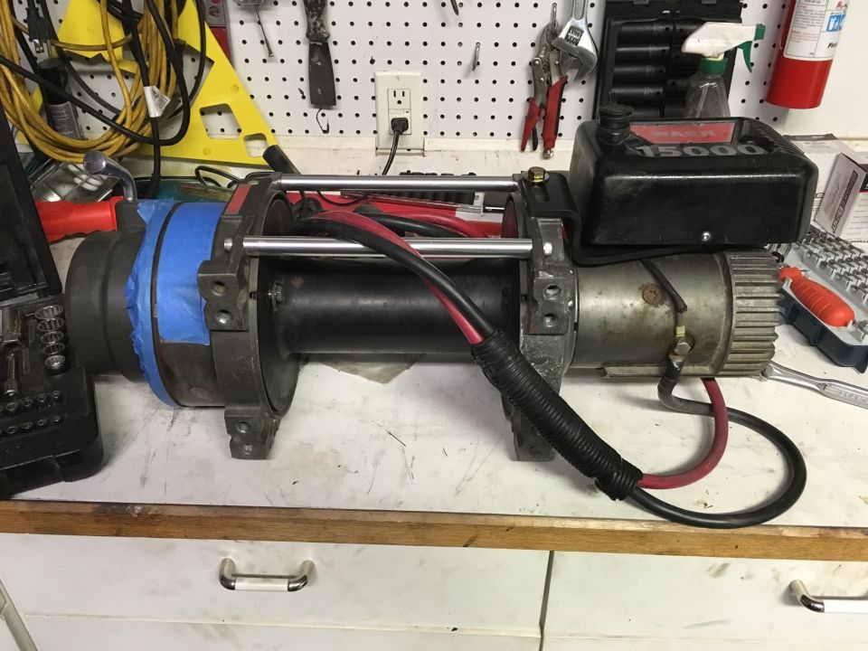 Warn 15000 winch with red and black cables on a workbench.