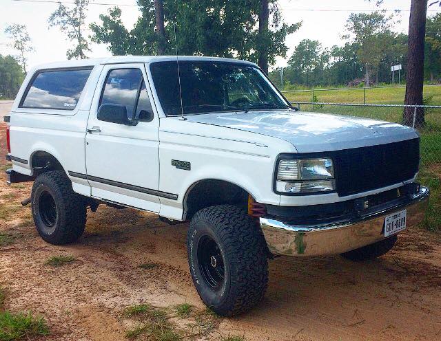 White 1996 Ford Bronco parked on a dirt road.