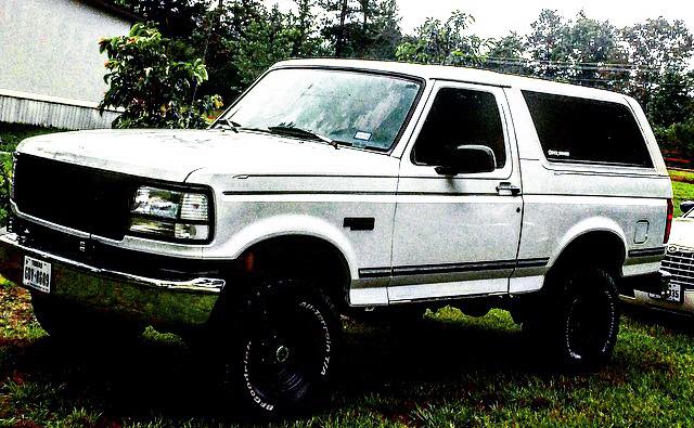 White 1990s Ford Bronco parked on grass.
